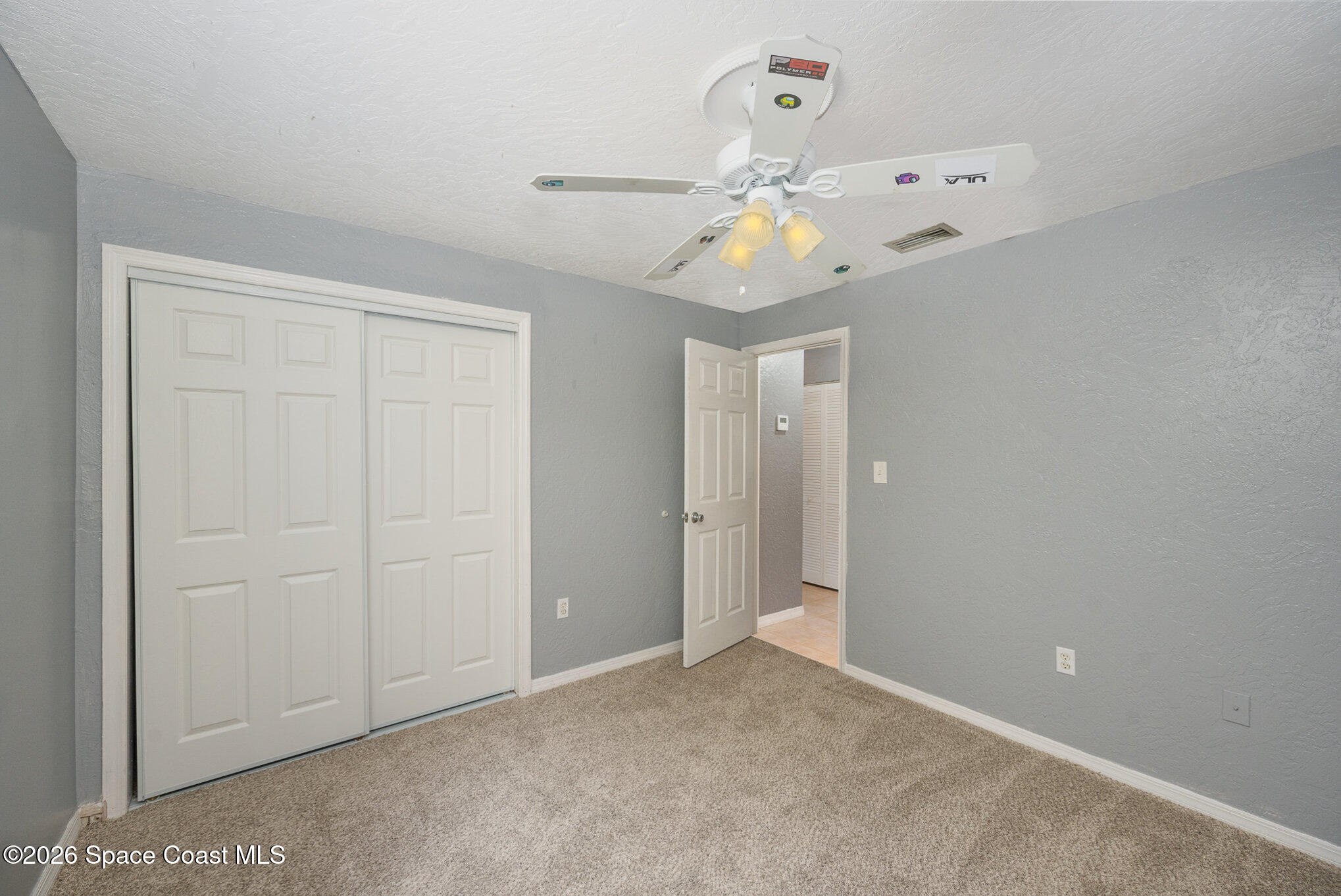 696 Las Palmas Way Melbourne, FL 32940 - Photo 18 of 21 an empty room with a chandelier fan and wooden floor
