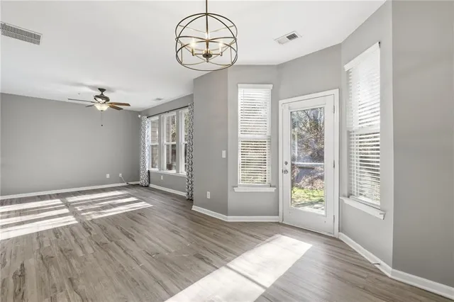 a view of an empty room with wooden floor and window