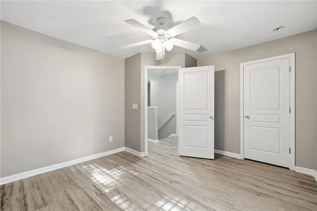 an empty room with wooden floor and ceiling fan