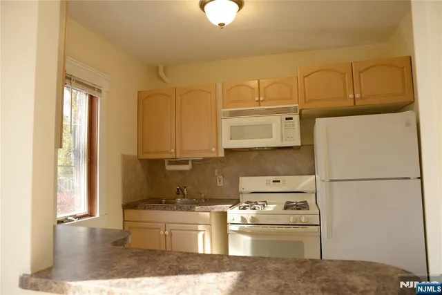 a kitchen with stainless steel appliances granite countertop a refrigerator a stove and white cabinets with wooden floor