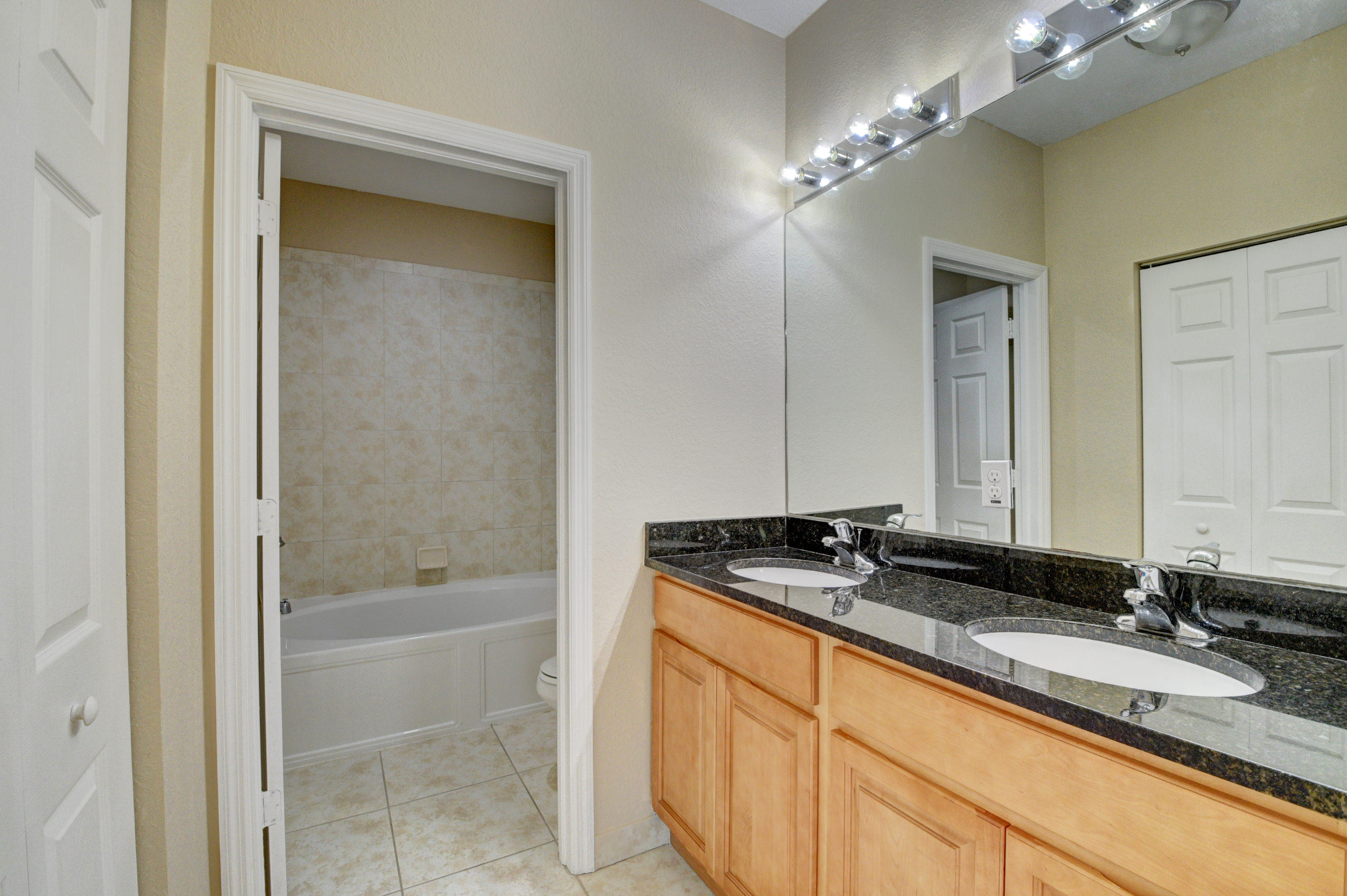 116 Williams Court Palm Springs, FL 33461 - Photo 9 of 17 a bathroom with a granite countertop sink a mirror and a bathtub