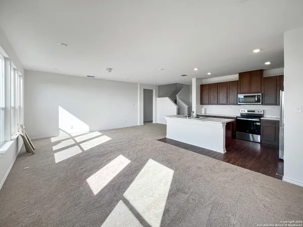 a living room with stainless steel appliances kitchen island granite countertop a refrigerator sink and cabinets