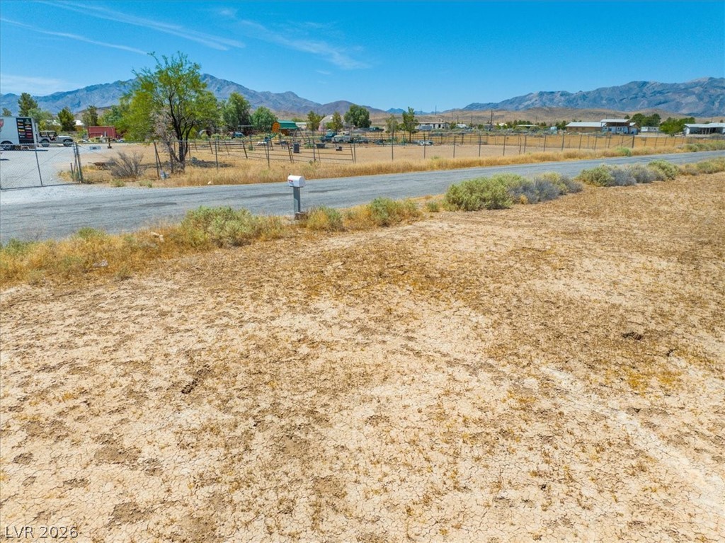 4580 Lawrence Road Pahrump, NV 89048 - Photo 9 of 40 An arid lot awaits your vision, bordered by a road and distant mountains.