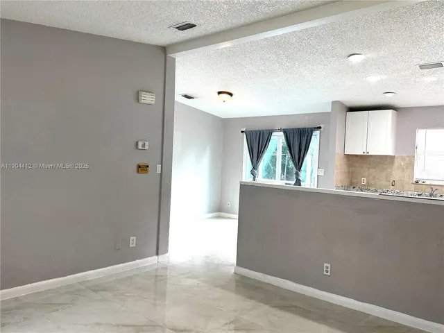 a kitchen with granite countertop white cabinets and window