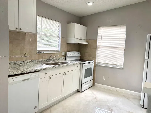 a kitchen with kitchen island granite countertop white cabinets and white appliances