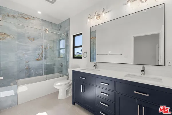 a spacious bathroom with a double vanity sink toilet mirror and bathtub