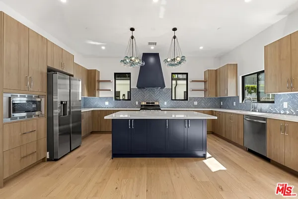 a large kitchen with kitchen island a large counter space a sink stainless steel appliances and cabinets