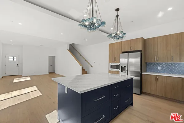 a kitchen with counter top space stainless steel appliances and wooden floor