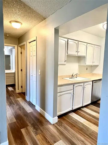 a view of a hallway with wooden floor and cabinet