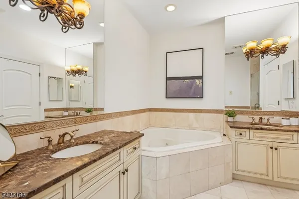 a bathroom with a granite countertop bathtub a sink and a mirror
