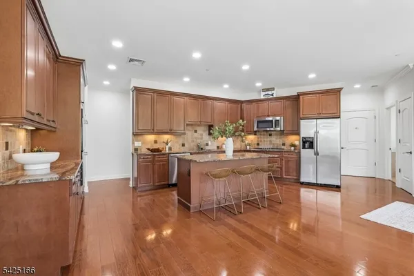 a kitchen with stainless steel appliances kitchen island granite countertop a refrigerator and a stove top oven