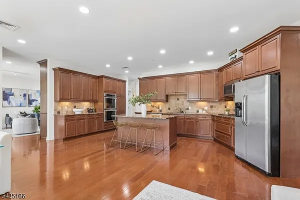 a kitchen with stainless steel appliances a refrigerator a stove top oven a sink cabinets and a dining table with wooden floor