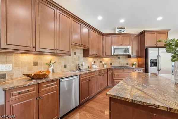 a kitchen with kitchen island granite countertop wooden cabinets stainless steel appliances a sink and a counter top space