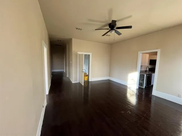 an empty room with wooden floor ceiling fan and windows