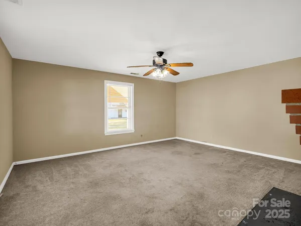 an empty room with windows and chandelier fan