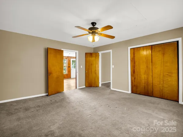 an empty room with windows and ceiling fan