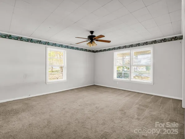 an empty room with windows and a ceiling fan