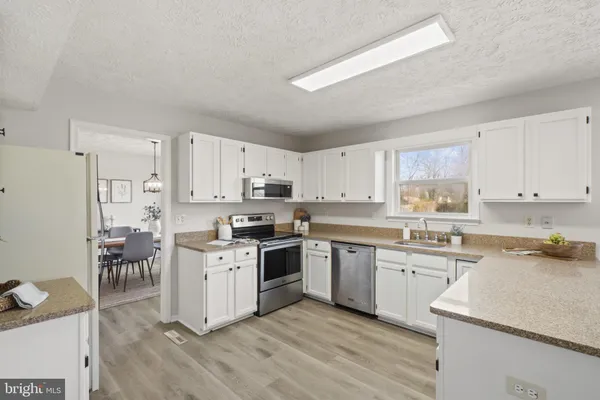 a kitchen with cabinets a sink and white stainless steel appliances