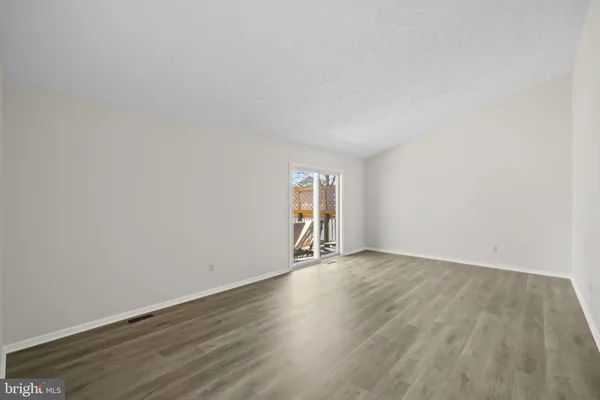 an empty room with wooden floor and window