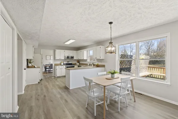 a dining room with furniture window wooden floor and stainless steel appliances