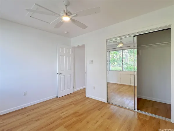 an empty room with wooden floor and a ceiling fan