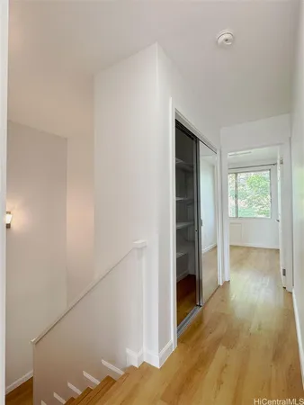 a view of hallway with wooden floor and cabinet