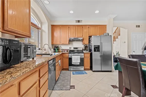 a kitchen with stainless steel appliances granite countertop a refrigerator a stove and a sink