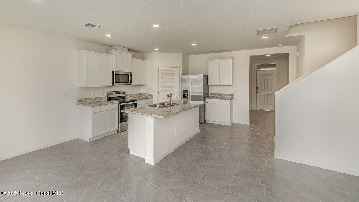 598 Ganley Street Palm Bay, FL 32908 - Photo 4 of 25 a kitchen with white cabinets and stainless steel appliances