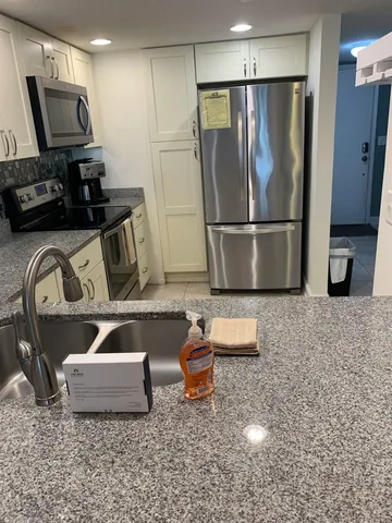 a kitchen with stainless steel appliances granite countertop a sink a refrigerator and a granite counter tops