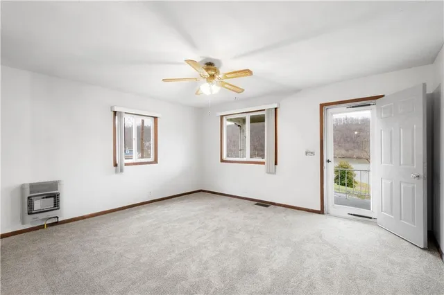 an empty room with windows and chandelier fan
