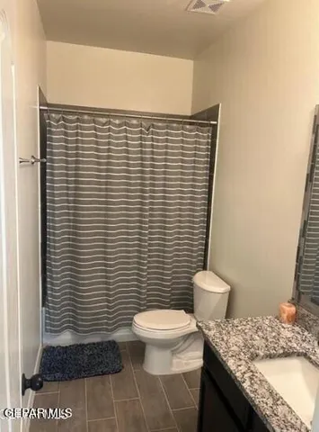 a bathroom with a granite countertop toilet and a sink