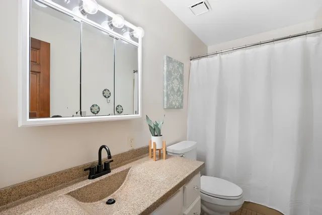 a bathroom with a sink a toilet and shower curtain