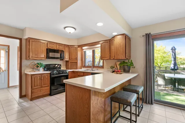 a large kitchen with granite countertop a stove top oven a sink dishwasher a dining table and chairs with wooden floor