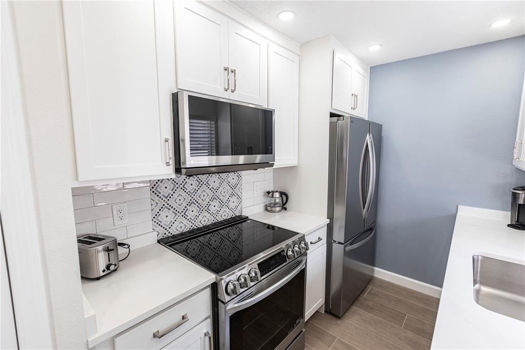 6020 Midnight Pass Road, Unit 29 Sarasota, FL 34242 - Photo 7 of 16 a kitchen with stainless steel appliances a refrigerator a stove a sink and a stove