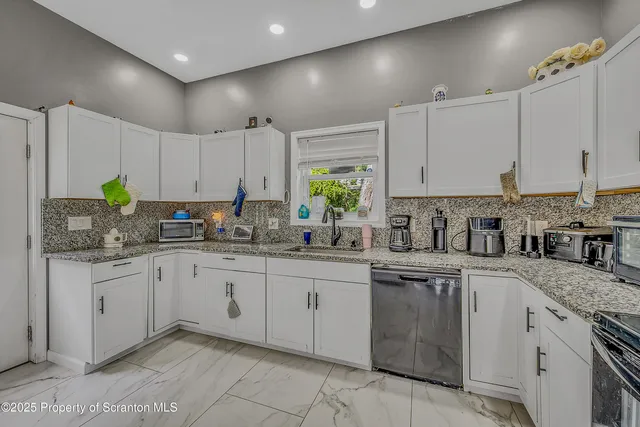 a kitchen with granite countertop cabinets stainless steel appliances a sink and a window