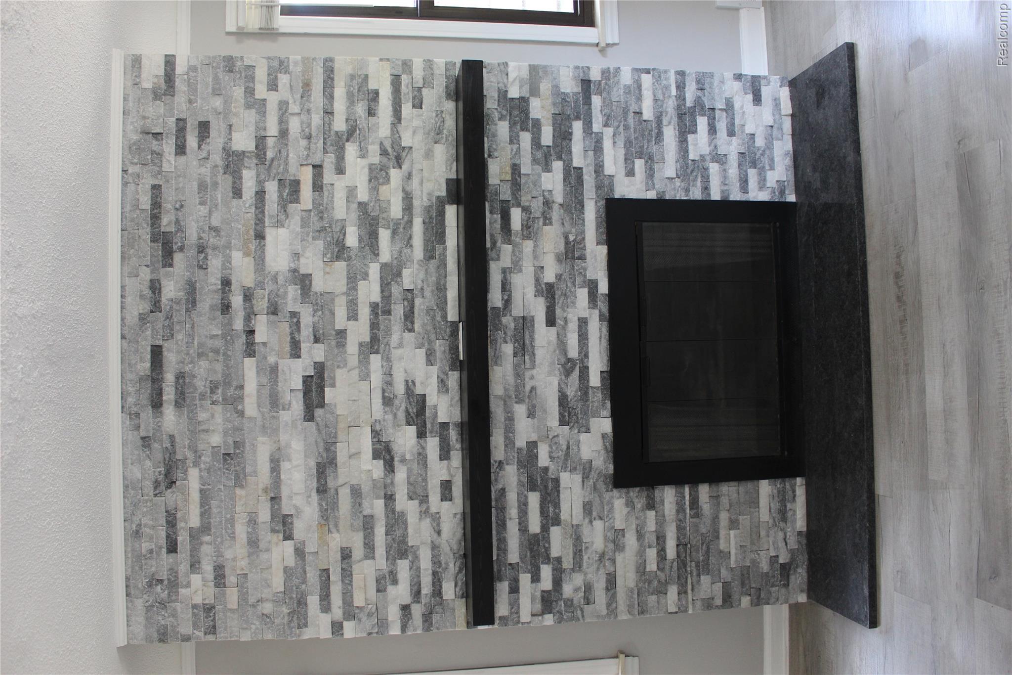 5543 Balfour Road Detroit, MI 48224 - Photo 26 of 54 Fireplace featuring a stacked stone surround in varied grey tones, a black mantle, and a black hearth