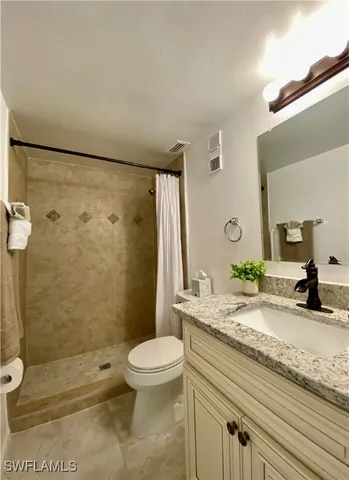 a bathroom with a granite countertop sink toilet and shower
