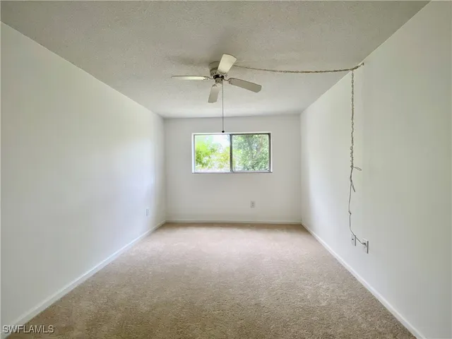 an empty room with windows and ceiling fan
