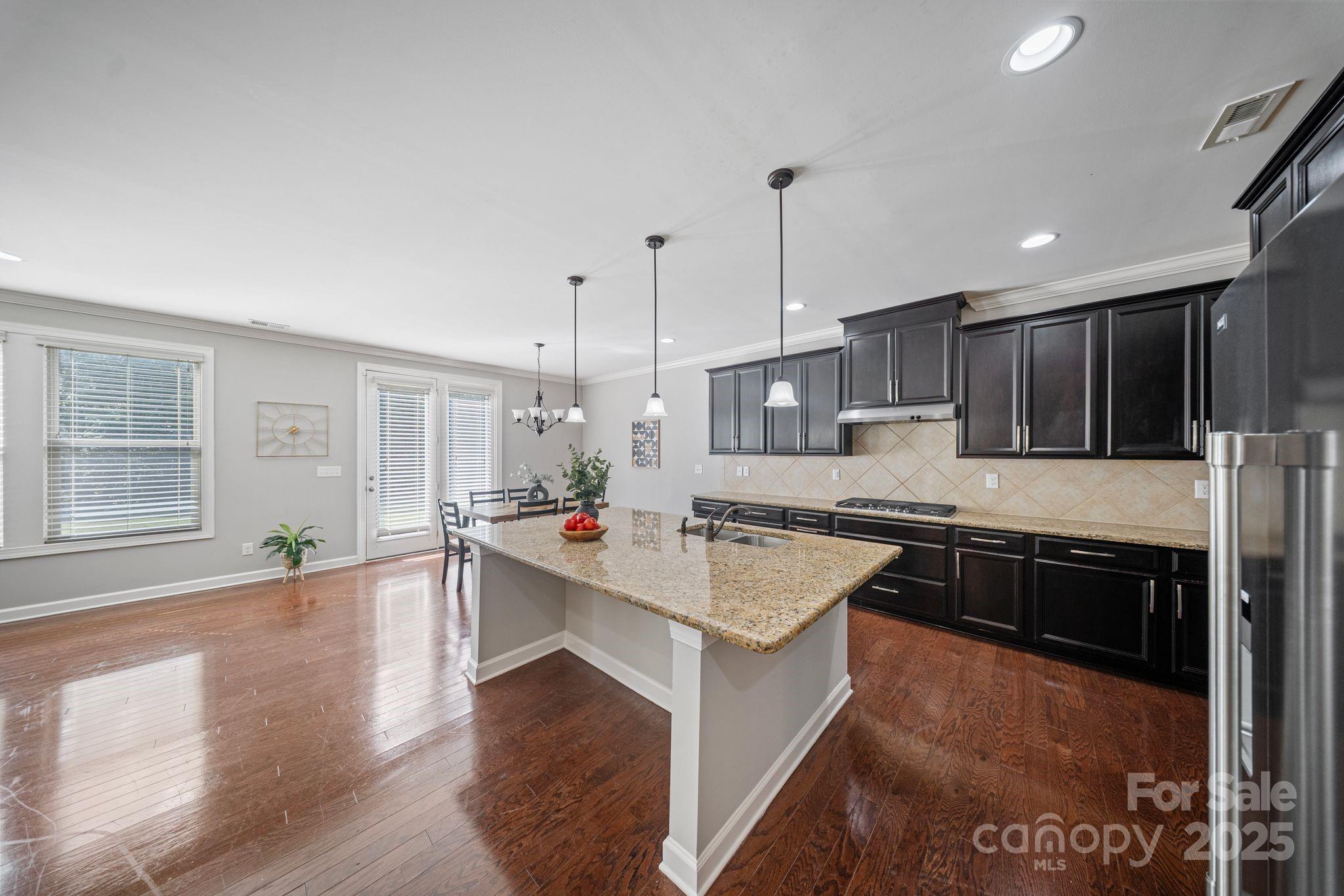 1433 Cilantro Court Tega Cay, SC 29708 - Photo 4 of 42 a large kitchen with stainless steel appliances granite countertop a sink stove oven and white cabinets with wooden floor