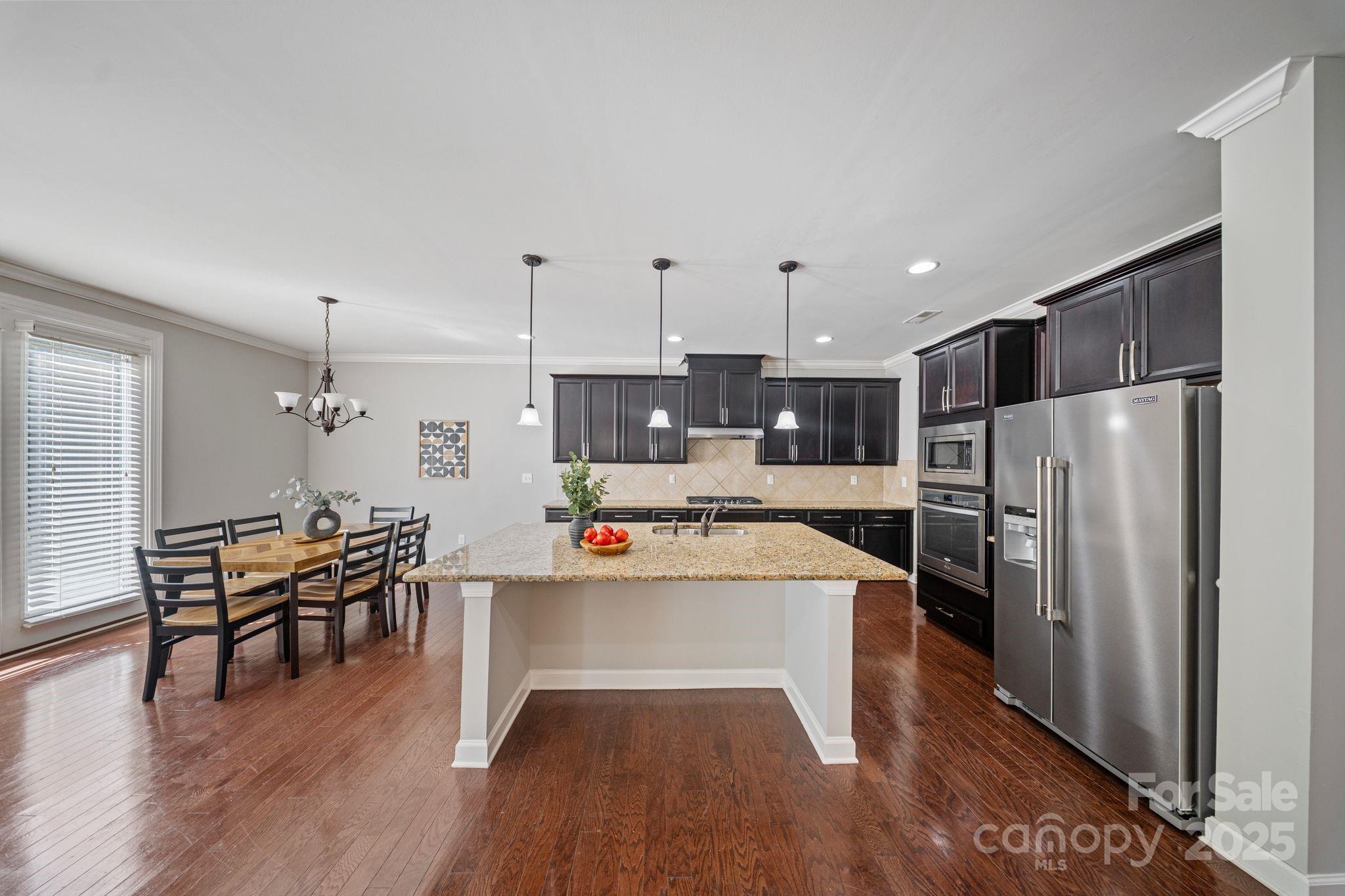 1433 Cilantro Court Tega Cay, SC 29708 - Photo 6 of 42 a kitchen with stainless steel appliances a stove a refrigerator a dining table and chairs with wooden floor