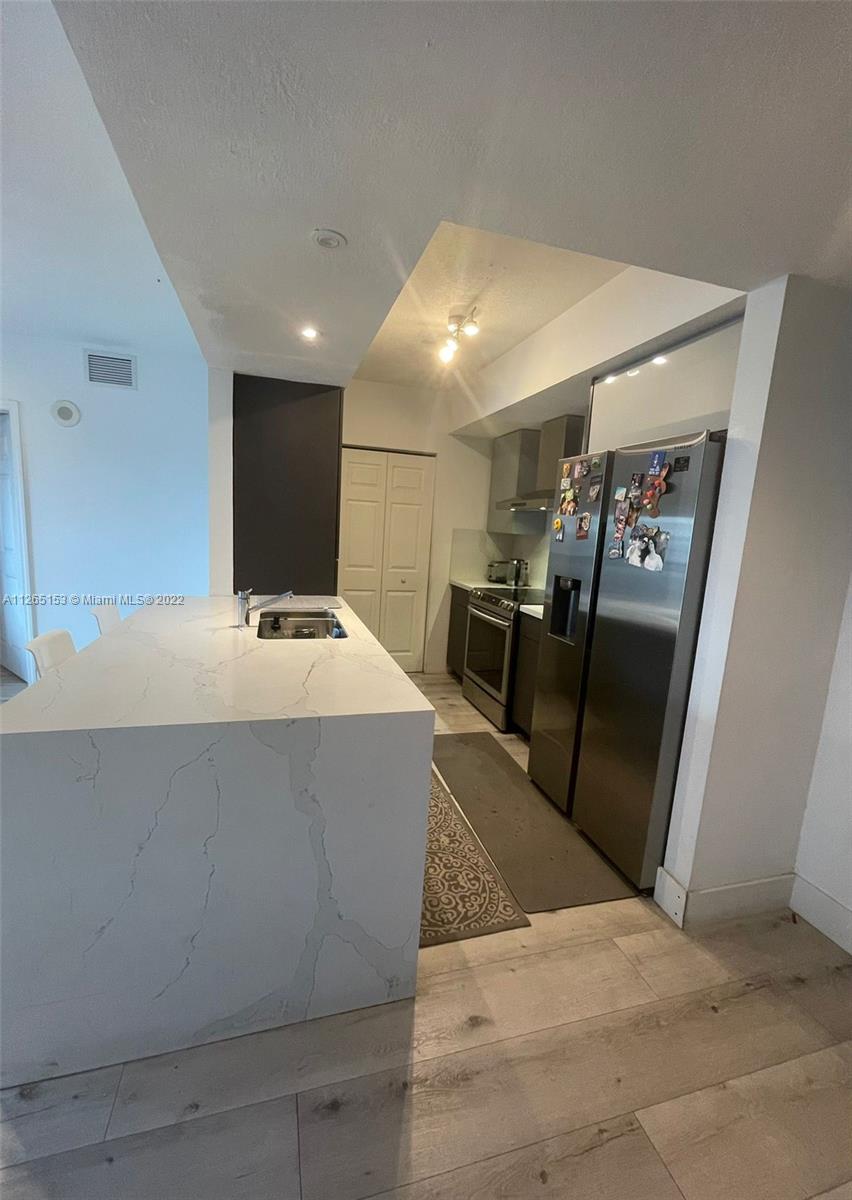4242 Northwest 2nd Street, Unit 708 Miami, FL 33126 - Photo 5 of 20 a living room with stainless steel appliances furniture a rug and a kitchen view