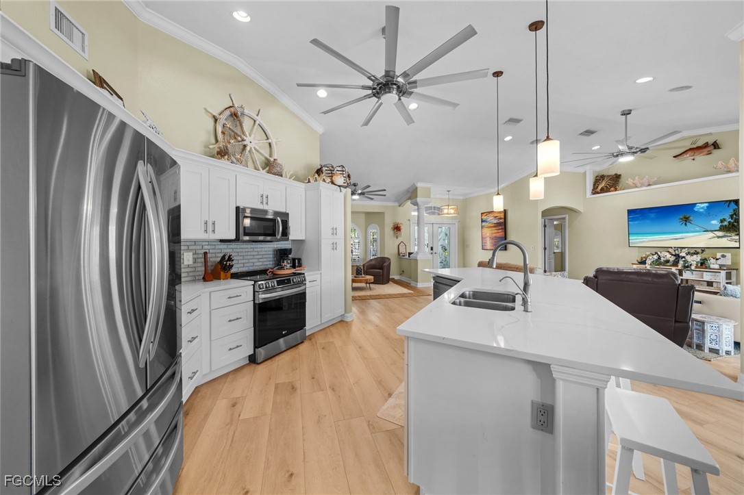 12234 Boat Shell Drive Matlacha Isles, FL 33991 - Photo 11 of 50 a kitchen with stainless steel appliances sink stove refrigerator and cabinets