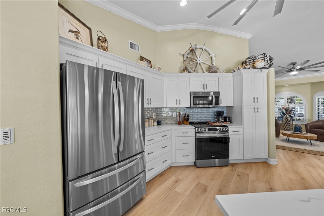 12234 Boat Shell Drive Matlacha Isles, FL 33991 - Photo 12 of 50 a kitchen with cabinets stainless steel appliances and wooden floor