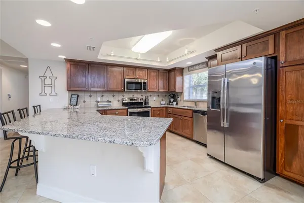 a kitchen with stainless steel appliances granite countertop a refrigerator a sink a stove a microwave and island