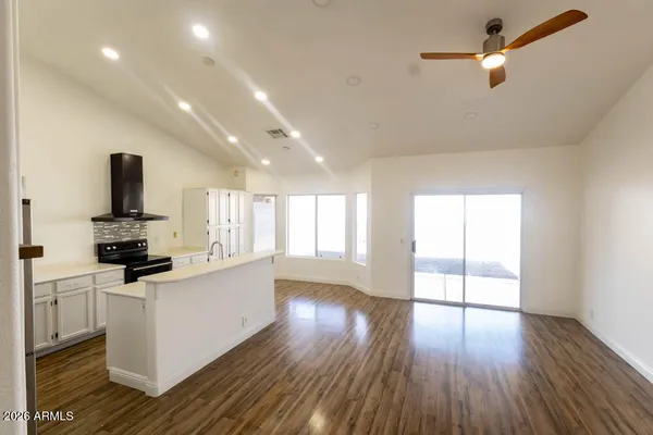 a view of empty room with wooden floor and fan