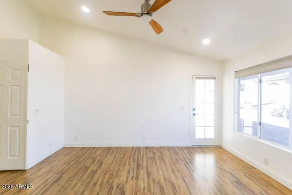 a view of an empty room with wooden floor and a window