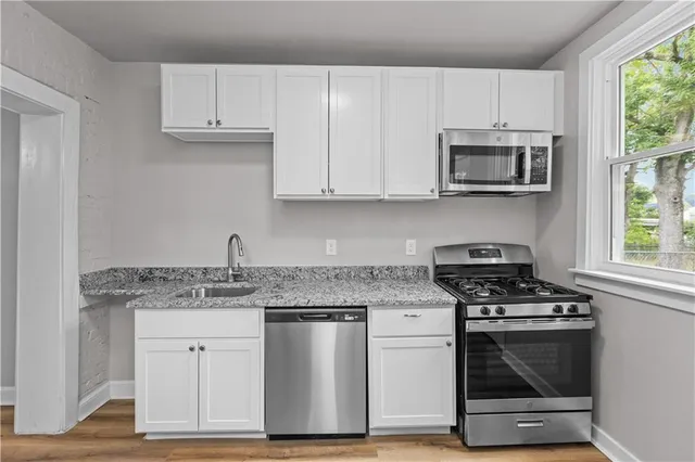 a kitchen with granite countertop a sink stove and microwave