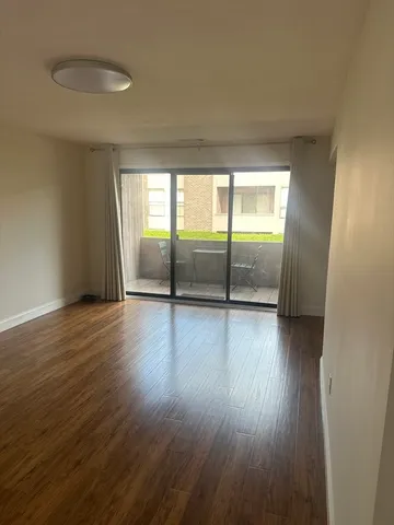 a view of an empty room with wooden floor and fan