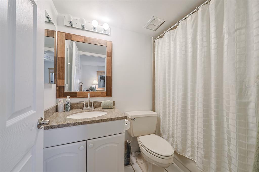19930 Gulf Boulevard, Unit 1B Indian Shores, FL 33785 - Photo 15 of 26 a bathroom with a granite countertop sink and a mirror