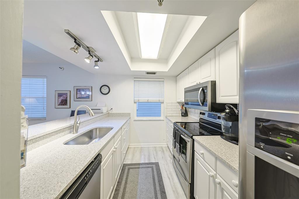 19930 Gulf Boulevard, Unit 1B Indian Shores, FL 33785 - Photo 8 of 26 a kitchen with a sink a counter top space stainless steel appliances and a window